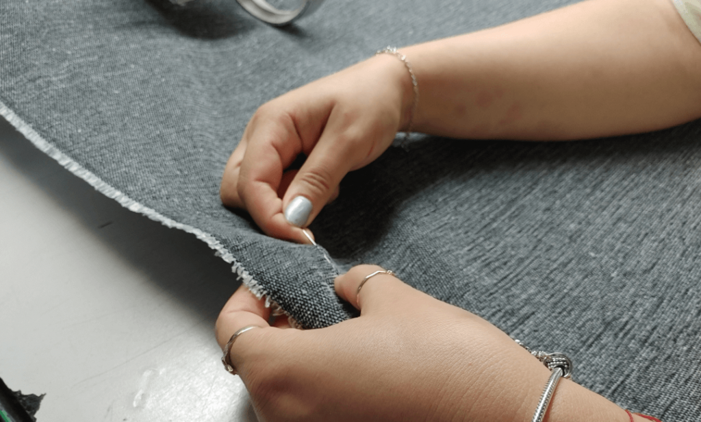 hands correcting fabric defects with a needle